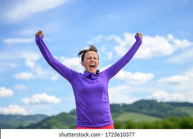 Exuberant happy woman celebrating spring during her daily workout jogging in the countryside against blue sky - Shutterstock ID 1723610377