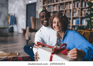 Exuberant interracial couple unwrapping a Christmas gift - Powered by Shutterstock