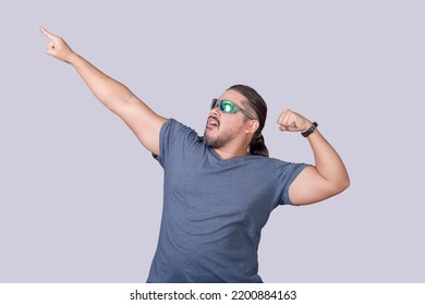 An exuberant and wild man poses pointing up while flexing his arms. A funny and burly guy in his 30s having fun and in a party mood, - Shutterstock ID 2200884163
