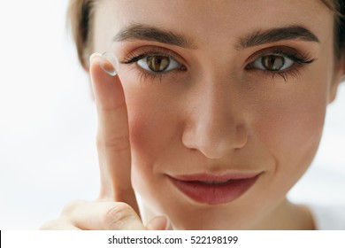 Eye Care And Contact Lenses For Eyes. Closeup Of Beautiful Woman Face With Smooth Skin And Perfect Makeup Applying Eyelens With Finger. Female Model Putting In Contact Eye Lens. Vision And Health