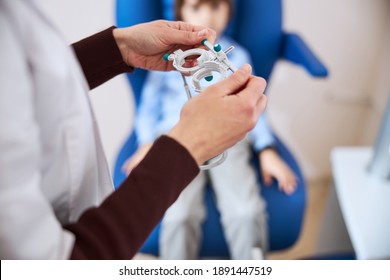 Eye Doctor Completing The Height And Length Adjustments Of A Trial Frame For Her Minor Patient