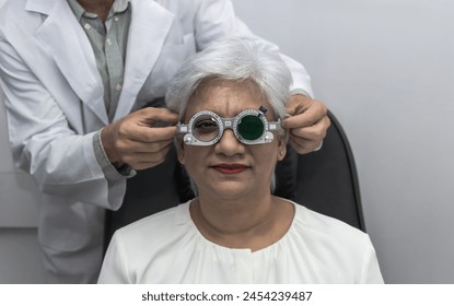 Eye doctor putting trail frame glasses doing eye exam with old patient woman in optical clinic - Powered by Shutterstock