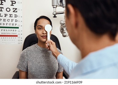 Eye exam, vision testing at an optometrist with young woman and doctor. Opthamologist using an occluder to test eyesight before being fitted with glasses. Relaxed lady smiling, satisfied with - Powered by Shutterstock