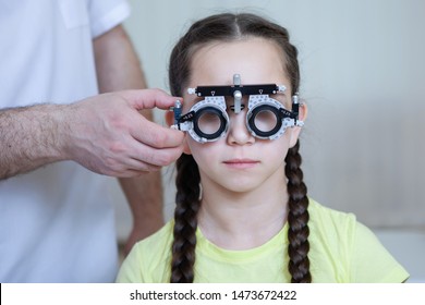 Eye examination by Ophthalmologist test glasses frame for a teenager girl in a yellow t-shirt with braids.