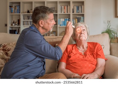 Eye examination. Senior patient assessment, doctor makes a home visit to check for a stroke in an elderly lady at a residential home. FAST test.  - Powered by Shutterstock