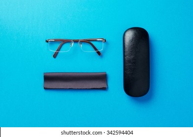 Eye Glasses, Case And Fabric Organized Over Blue Background, Above View.