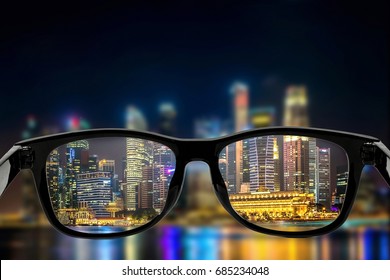 Eye glasses looking to night city view , focused on glasses lens - stock image , Vision concept.