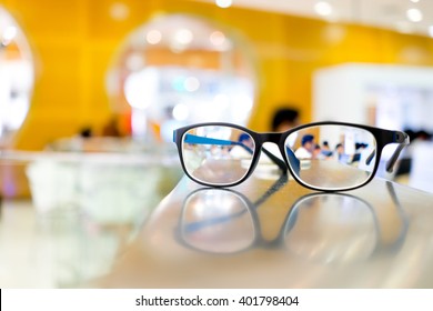 Eye Glasses On Table In Library, Can See People Reading Books Through The Lens