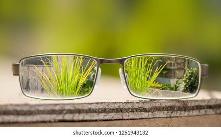 Eye Glasses Placed On Top Of A Wooden Table To See Through The Background