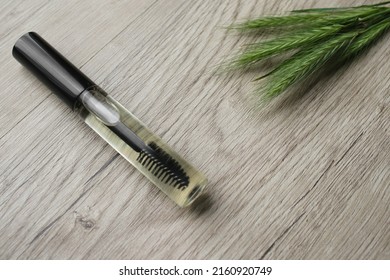 Eye Lash Gel Serum. Serum Essence Essential Oils To Eyelashes For Growth Strong Effect Solution. Mock-up With Green Wheat On Wooden Background