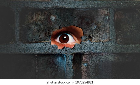 Eye looking through the hole on cracked wall. Spy peeking through hole in brick wall. Spy concept.