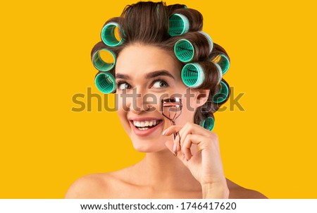Eye Makeup. Cheerful Housewife Holding Eyelashes Curler Doing Beauty Routine Posing Over Yellow Background. Studio Shot
