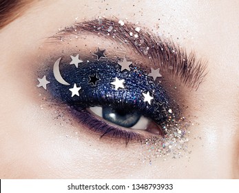 Eye makeup woman with decorative stars. Perfect makeup. Beauty fashion. False Eyelashes. Cosmetic Eyeshadow. Make-up detail. Eyeliner. Creative make-up the night sky with stars