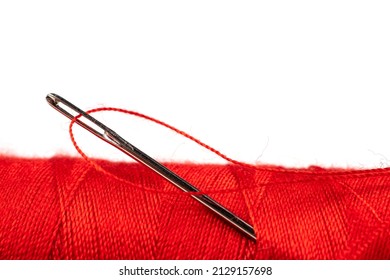 Eye Of The Needle With Red Polyester Thread. Spool Of Red Polyester Sewing Thread In The Background. Selective Focus. Bokeh.