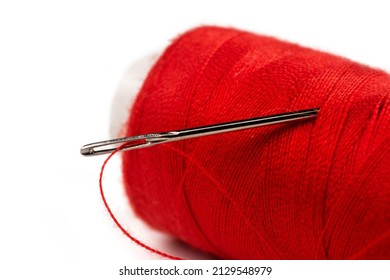 Eye Of The Needle With Red Polyester Thread. Spool Of Red Polyester Sewing Thread In The Background. Selective Focus. Bokeh.