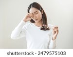 Eye problem concept, fatigue asian young woman tired eyes irritated rubbing, massage eye dry relief vision pain after work, eye strain, hand holding glasses, suffer bad blurry isolated on background.