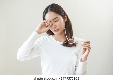 Eye problem concept, fatigue asian young woman tired eyes irritated rubbing, massage eye dry relief vision pain after work, eye strain, hand holding glasses, suffer bad blurry isolated on background. - Powered by Shutterstock