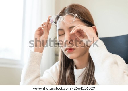 Eye problem concept, fatigue asian young woman tired eyes, irritated rubbing eye dry relief vision pain after work on laptop computer, eye strain, hand holding glasses, suffer migraine, bad blurry