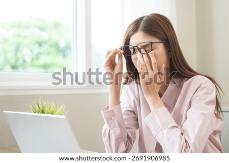 Eye problem concept, fatigue asian young woman tired eyes, irritated rubbing nose, relief vision pain after work on laptop computer, eye strain, hand holding glasses, suffer migraine, bad blurry.