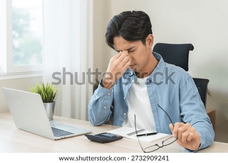 Eye problem concept, fatigue asian young man, male tired eyes, irritated rubbing nose, relief vision pain after work on laptop computer, eye strain, hand holding glasses, suffer migraine, bad blurry.