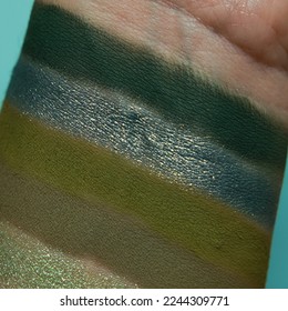 Eye shadow swatches  dry powder  set sage green metallic brush strokes skin  Cosmetic makeup texture samples  smear trace samples pink background  Realistic photography