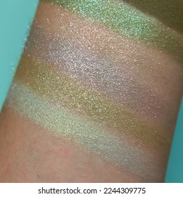 Eye shadow swatches  dry powder  set sage green metallic brush strokes skin  Cosmetic makeup texture samples  smear trace samples pink background  Realistic photography