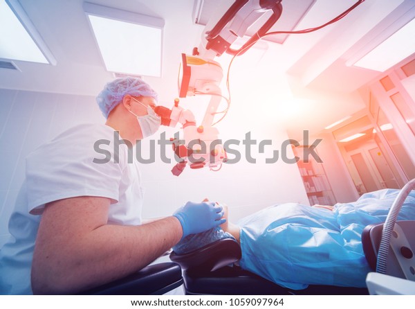 Eye surgery. A patient and surgeon in the\
operating room during ophthalmic surgery. Patient under surgical\
microscope. Vision\
correction