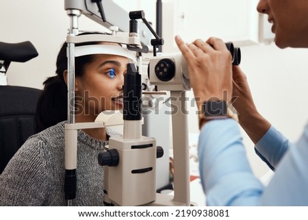 Eye test, exam or screening with an ophthalmoscope and an optometrist or optician in the optometry industry. Young woman getting her eyes tested for prescription glasses or contact lenses for vision