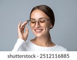 Eye wear fashion. Eyeglasses, optic, healthy vision concept  Portrait of a young woman with brown hair wearing green transparent round spectacles and posing with a hand. 