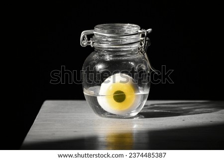 an eyeball inside a jar and placed on top of a wooden table