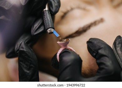 eyebrow microblading. A master in black gloves draws the pigment for the procedure the handpiece with a shading needle.