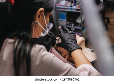 Eyebrow Microblading. A Master In Black Gloves Holds A Blending Needle Over The Brow Of The Model. Macro Photography