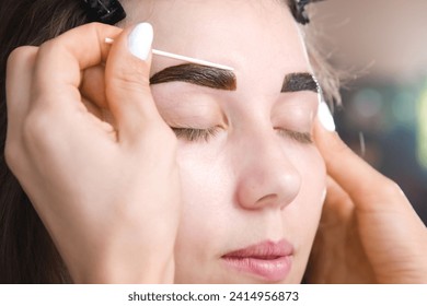 Eyebrow tinting. Close-up of a technician applying eyebrow dye or removing excess paint. Cosmetic procedures, eyebrow makeup in a beauty salon by a professional - Powered by Shutterstock