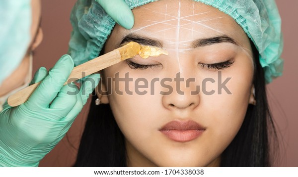 Eyebrow wax for hair removal. Cosmetic procedure.\
Beauty and health. Bright skin. Brow architecture in the salon of a\
beautician-makeup\
artist.
