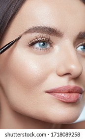 Eyebrows Makeup. Woman Shaping Brows With Cosmetic Brush. Beautiful Girl Close Up Portrait. Female With Perfect Skin And Blue Eyes.
