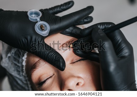 Eyebrows microblading concept. Cosmetologist preparing young woman for eyebrow permanent makeup procedure.
