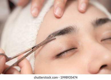 Eyebrows Trimming Service In Spa Salon, Face Hair Cutting And Trim With Small Scissor Tool For Facial Beauty Women Closeup.