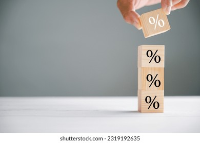 Eye-catching image capturing the concept of interest rate and mortgage rates. Businessman's hand putting a wood cube block with a percentage symbol icon, symbolizing the fluctuating nature of rates.