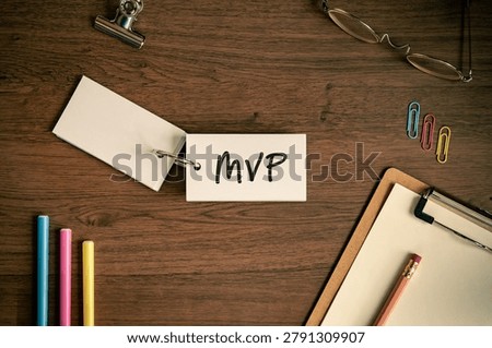 Eye-catching image of MVP text on word card. The word stands for Minimum Viable Product. Shown with pens, clips, clipboard.