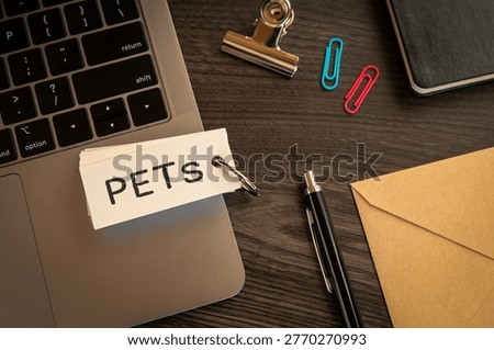 Eye-catching image of PETs text on word card. The word stands for Privacy Enhancing Tech. Shown with clips, laptop, pen.