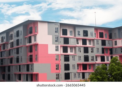 Eye-catching modern building facade featuring a blend of pink and gray colors. The unique design showcases geometric shapes and lines in an urban setting.