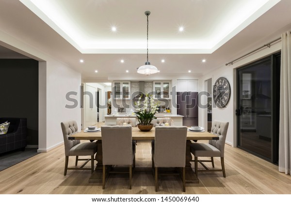 An eye-catching view of contemporary\
dining area attached to a modular kitchen having a 6-seater dining\
table with a bright pendant light hanging above\
it.