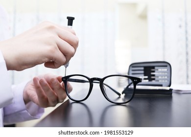 Eyeglass repair. Close-up of the hand of a master who uses a screwdriver to tighten a screw in a spectacle frame. Optics salon and repair shop - Shutterstock ID 1981553129