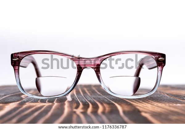 Eyeglasses with bifocal lenses, plastic frame, on\
wooden board