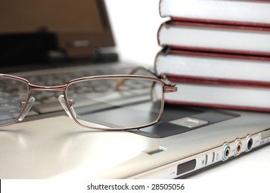 Eyeglasses and books on the laptop