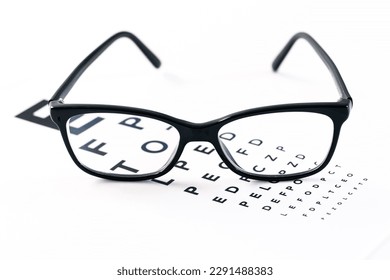 Eyeglasses with eye test table on white, optometrist concept and eye test