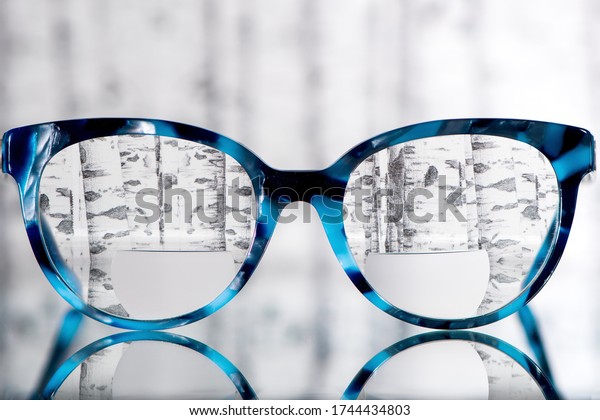 Eyeglasses Glasses with\
Bifocals and Black blue Frame smudged agaist birch trees. Blurry\
Vision Concept
