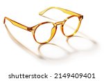 Eyeglasses in orange golden bright color in transparent plastic. Eyewear side view with shadow. Trendy glasses isolated on white background. Fashion spectacles for man and woman