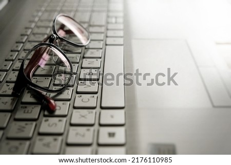 The eyeglasses are placed on the keyboard keys.