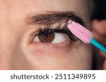 Eyelash Extension. combing the extended eyelashes. A girl with brown eyes does a close-up makeup. Eyelash Care Treatment: eyelash lifting, staining, curling, laminating and extension for lashes.